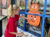 Ava Peterson works on a pumpkin painting on the windows at Countryside Framing and Gallery.