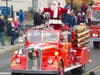 Santa is escorted through town aboard an antique fire engine.