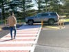 As resident Charlie Feuer approaches the pedestrian refuge a vehicle illegally crosses over the crosswalk. Vehicles in both directions are required to stop when a pedestrian enters a crosswalk.