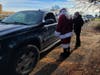Gene and Santa hand out $100 bills at a food distribution site in Levittown.