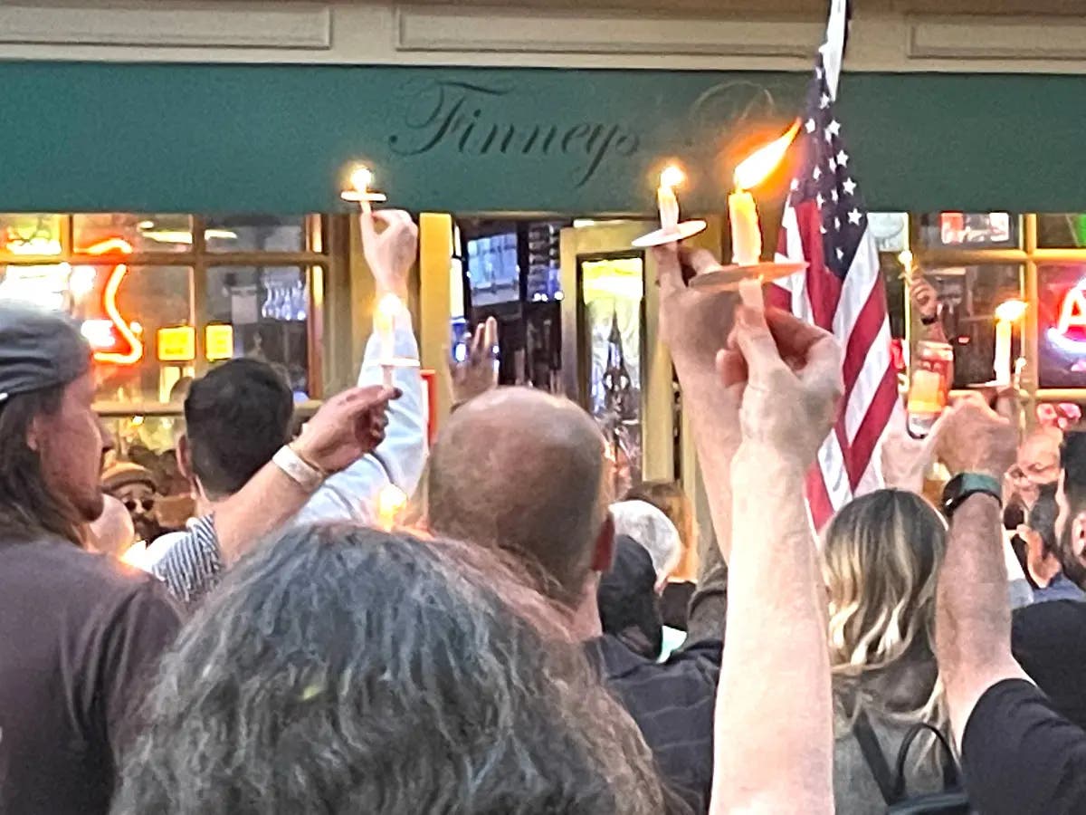 Friends, family and colleagues of the late Richie Wylie raise their candles outside of Finney's Pub in Doylestown in memory of the bar manager.
