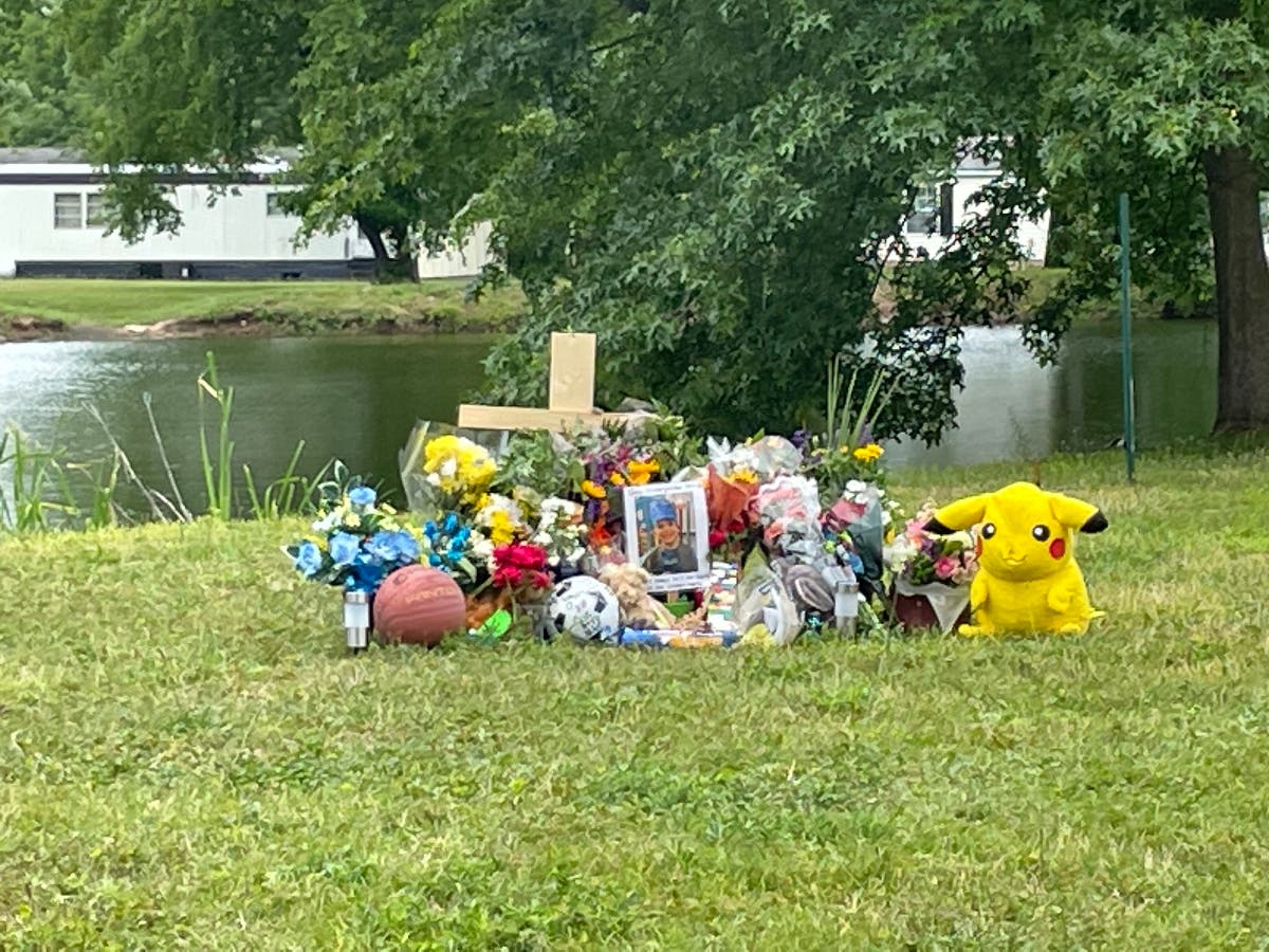 A makeshift memorial to Joey Malcolm Jr. grows on the banks of the pond.