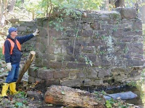 Mike Sellers, the president of the Newtown Creek Coalition, stands next to a remnant of the stone trolley bridge that once crossed the Newtown Creek at Frost Lane.