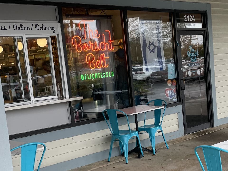The Borscht Belt Deli neon sign in the front window of the Village at Newtown South store.
