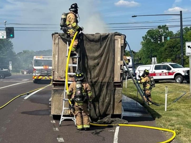 A firefighter pours water into the smoldering tractor-trailer on Route 202.