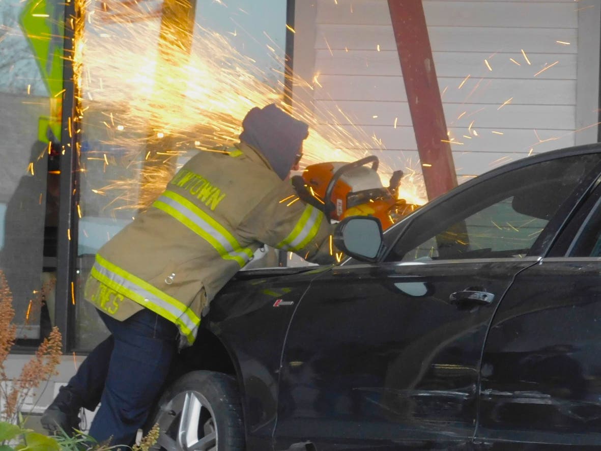 Sparks fly as a Newtown firefighter uses a metal cutting saw to free the car from the debris.
