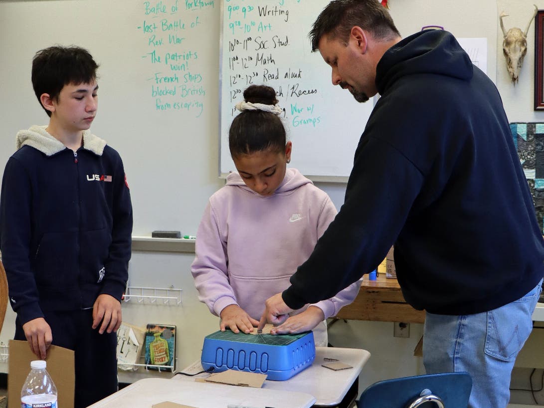 A teacher works with students with a ChompSaw.