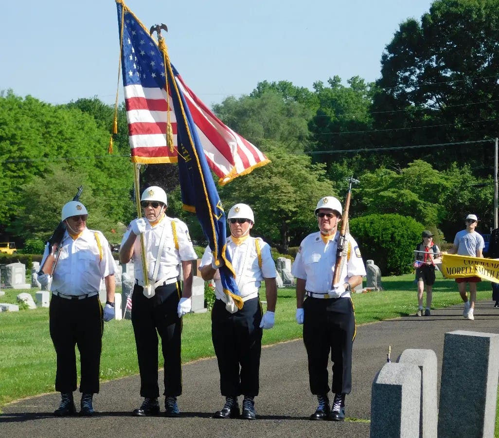 The American flag is carried past the rows of graves at the Newtown Cemetery.