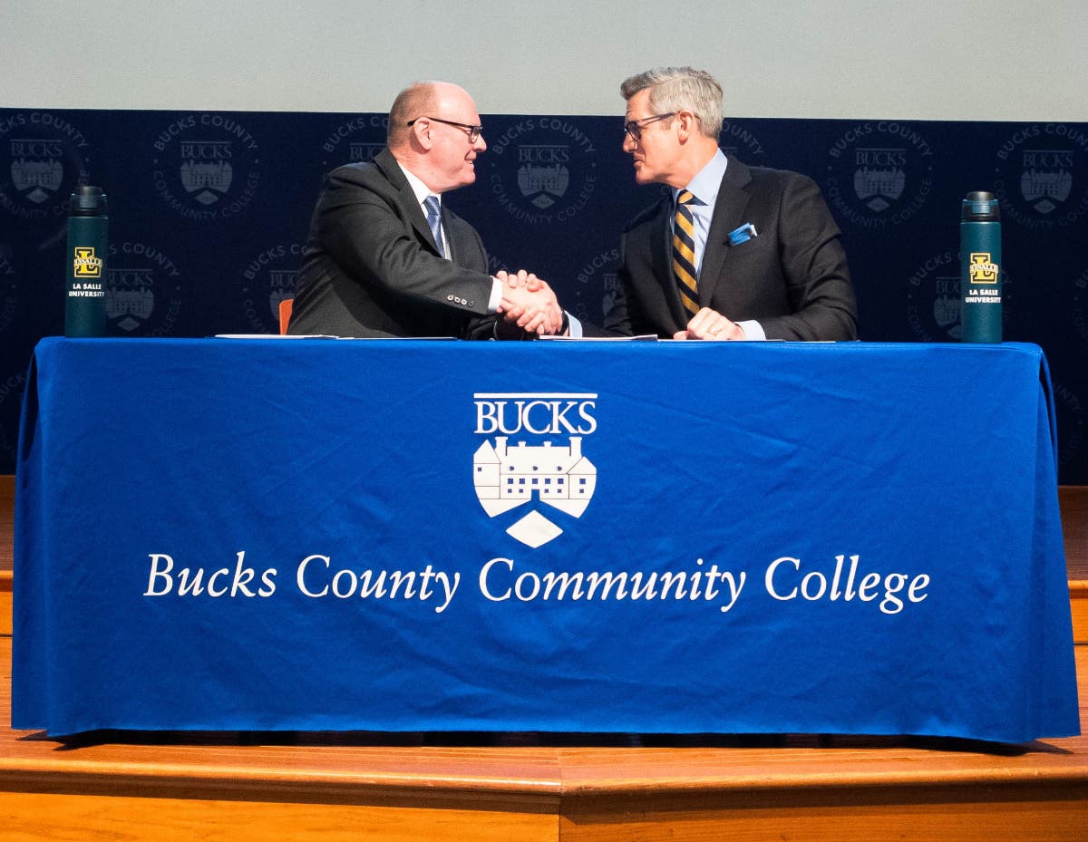 Bucks County Community College President and CEO Patrick M. Jones (left) and La Salle University President Daniel J. Allen (right) shake hands after signing the agreements.