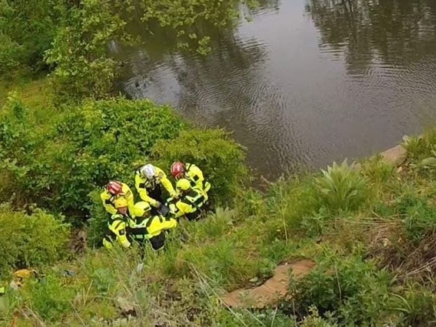 Rescuers work to bring the deceased man up the steep embankment.