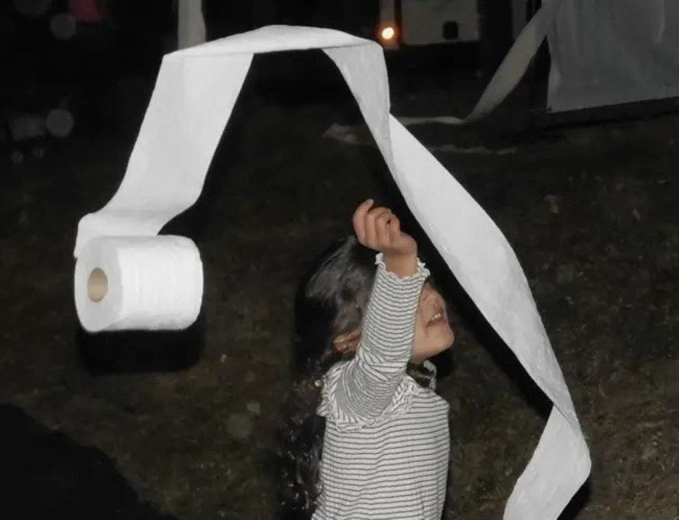 A youngster tosses a roll of toilet paper into the trees at Keith Fenimore's house in 2024.