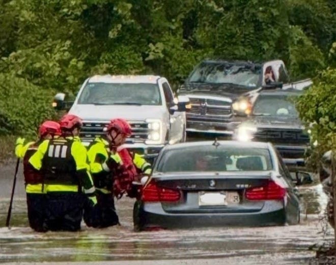 Volunteers with the Warwick Township Fire Company, in knee-deep water, assist a stranded motorist.