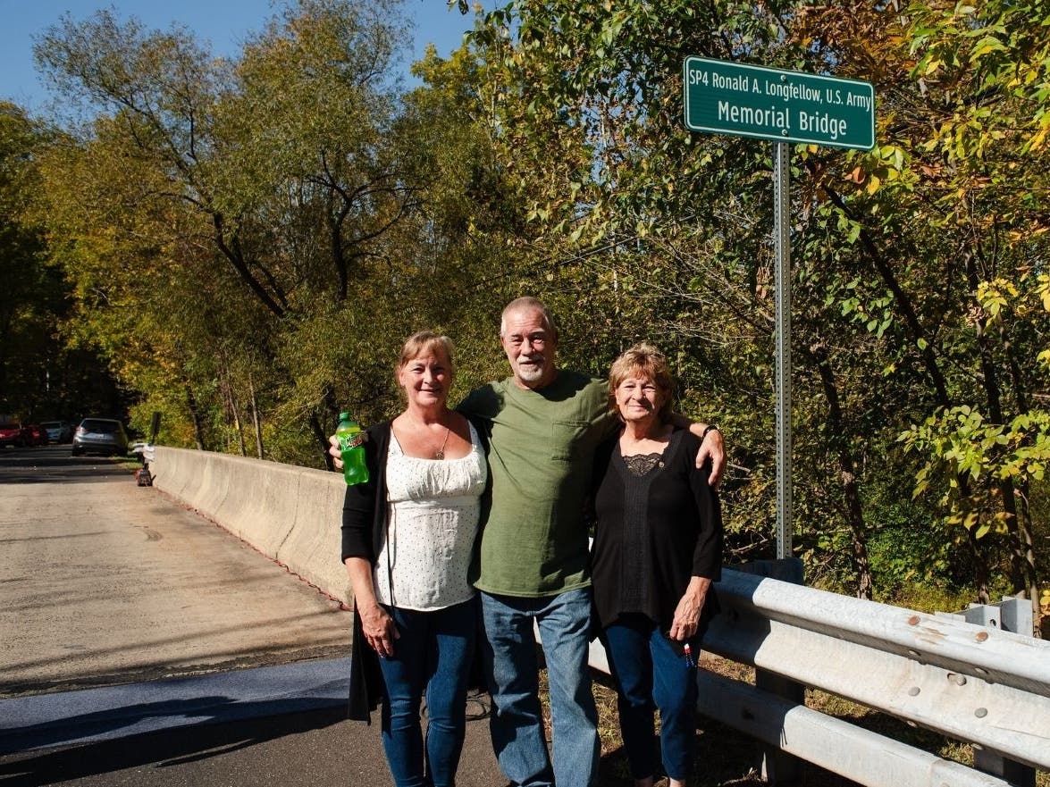 Family members gather next to the sign bearing the name of U.S. Army SP4 Ronald Anthony Longfellow.