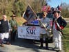 Four Members of the Sgt Maj John Champe Chapter in front of the float showing the banner.  L-R: Warner Workman, Mark Sink, Barry Schwoerer, Ken Bonner.  Mr. Schwoerer is holding a replica guidon of the US Light Dragoons.
