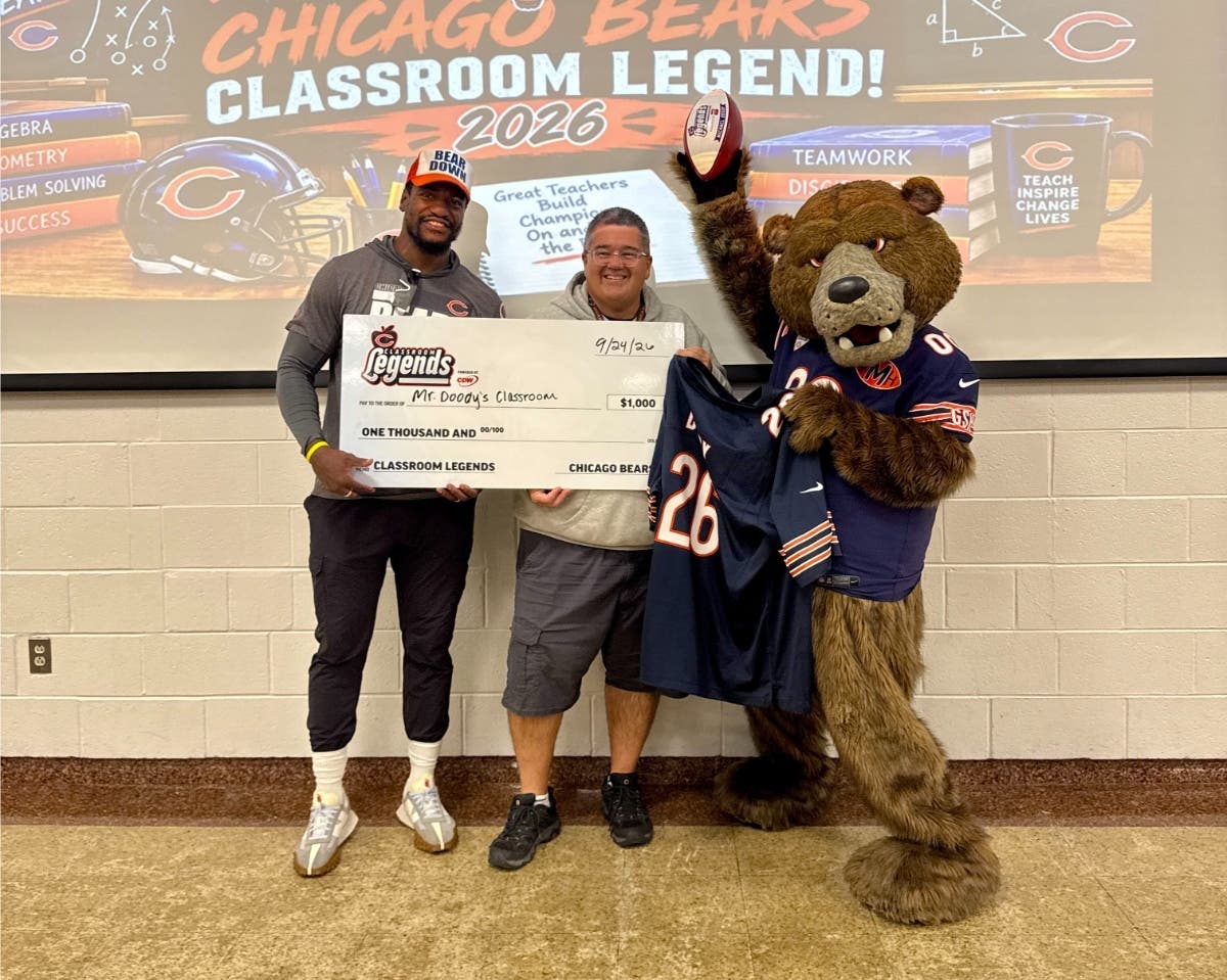 Mike Doody poses with former player Christian Jones and mascot Staley Da Bear after being recognized as a Chicago Bears Classroom Legend during a surprise presentation at Hilda Walker Intermediate School on September 24. 
