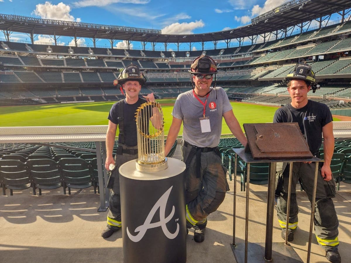 Cherokee County Fire Apparatus Operator Beau Witcher, Fire Capt. Ric Mitchell and FAO Lucas Vasquez stand with the Atlanta Braves' 2021 World Series trophy Sunday at Truist Park. The group attended a 9/11 Memorial Stair Climb.