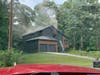 Light smoke comes from the roof and upper-level window as Cherokee County firefighters tend to a fire Friday at an Acworth house.