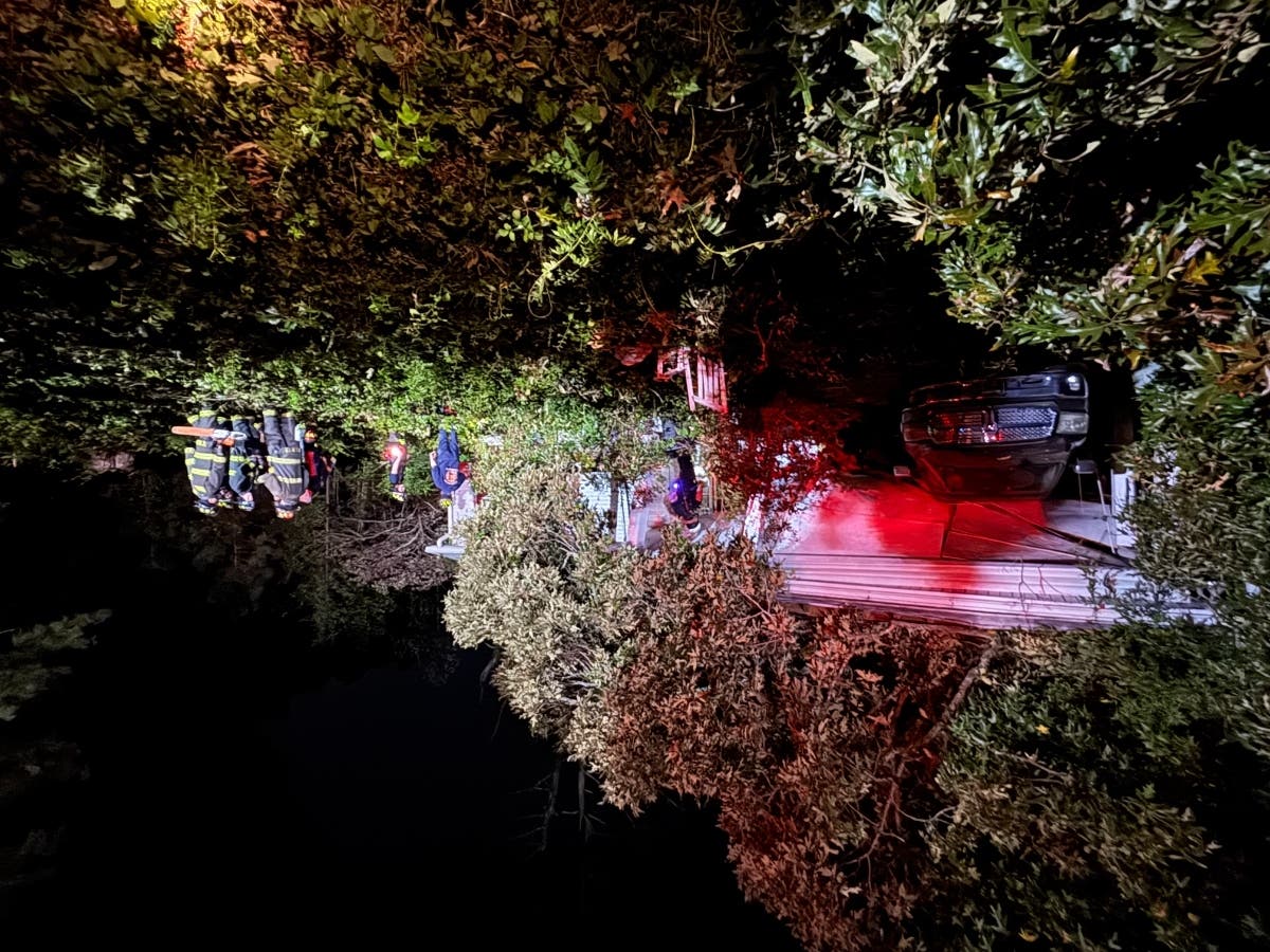 Cherokee County firefighters work to free a trapped resident inside a home after a tree came down on the home around 8:30 p.m. Tuesday in Holly Springs.