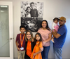 B1C participants, The Jumique family, pose in front of their photo with Elena Perez Moreno, B1C’s Development Director. 