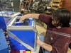 Housatonic Community College Advanced Manufacturing instructor Tristan Hunte sits at a 3-D printer making face shield frames to help healthcare workers in the fight against COVID-19.