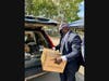 HCC Chief Executive Officer Dr. Dwayne Smith loads a 40-pound box of groceries into a waiting car.