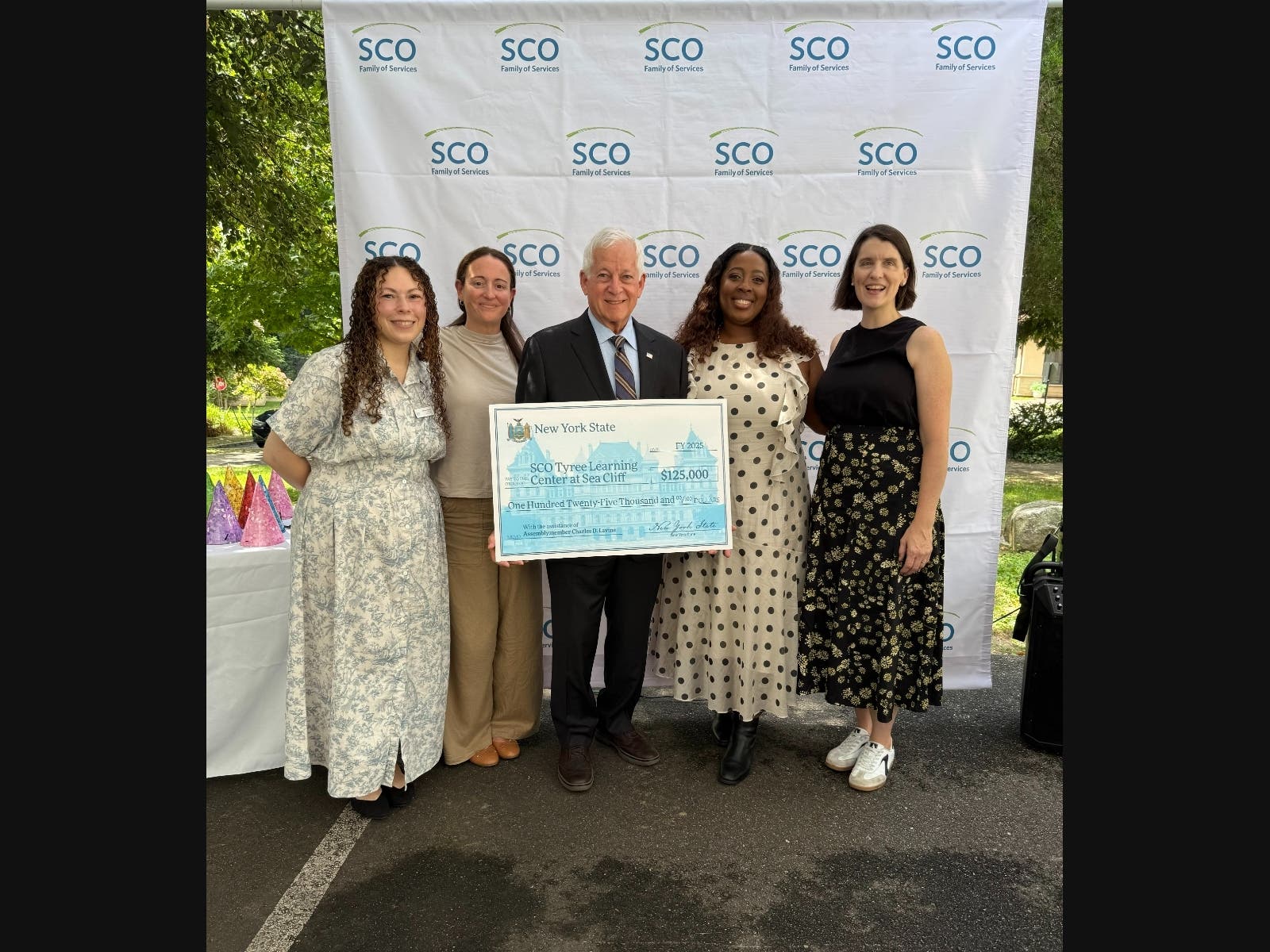 Assemblymember Charles Lavine presents check to Suzette Gordon, SCO Family of Services President and CEO (next to Lavine / second from right) and other members of her staff, September 10, 2026