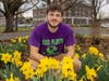Rutgers senior Josh Kover crouches in a patch of daffodils outside Blake Hall in New Brunswick, N.J.