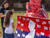 Jessie Garcia (left) speaks with a girl looking at a collaborative mural featuring a map of New Jersey and flags during the Wash and Learn end-of-year celebration in New Brunswick.