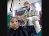 Third grader Dmitri Hurrings gets a haircut for the holidays at Illinois School. The free haircuts were provided by the Phipps Academy of Barbering located in Richton Park.