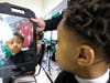 Fourth grader Kameron Bennett checks out his fresh haircut in the mirror during Holiday Haircuts at Illinois School in Park Forest.