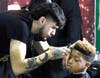 Fourth grader William Wheat gets his hair cut by one of the student barbers from the Phipps Academy who volunteered their time to give students at Illinois School haircuts.