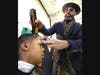 Kevin Phipps, owner of the Phipps Academy of Barbering, gives a haircut to 5th grader Ioannis Price.