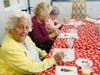A resident smiles while participating in a festive Paint and Sip activity in Lake Forest Park Senior Living’s Assisted Living community, creating holiday-themed artwork on a cheerfully decorated table.