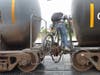 Cyclists climbs between two freight cars to cross the tracks at the Chestnut Avenue intersection.