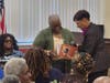 An unidentified member of the audience receives a free copy of Dr. Draper's novel 
about her grandfather's newspaper success.