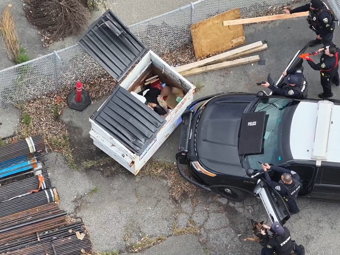 A suspect hides in a dumpster as officers surround him on Monday, April 20, in Fremont. 