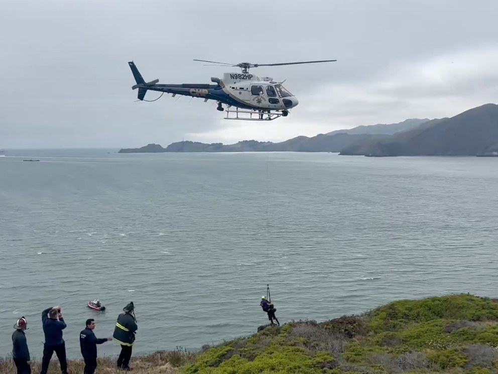 Fire officials use a helicopter to rescue two people trapped on a cliff near the Golden Gate Bridge on Monday. 