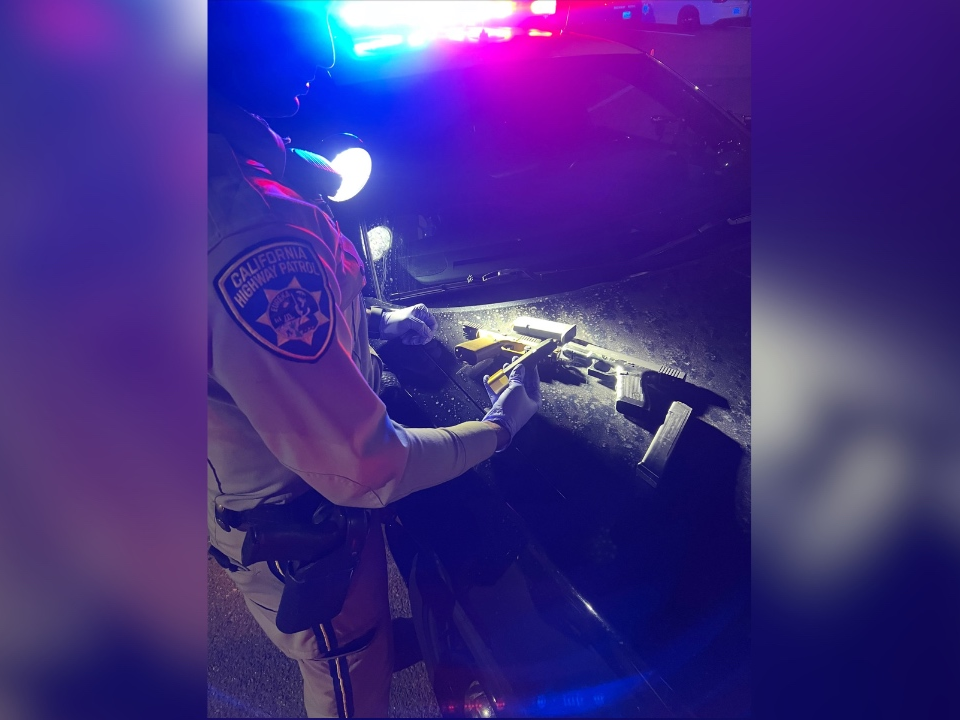 Officers inspect guns that the California Highway Patrol says were found during a traffic stop. 