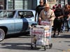 A man with a churro cart passes by a vintage car in the Mission during the annual King of the Streets event on Saturday, Sept. 19. 