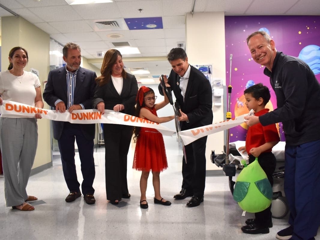 Liana Garcia (center), an 8-year-old patient, and her littler brother (right), help cut the ribbon at the unveiling of the UMass Memorial Medical Center Children's Medical Center's Dunkin' Joyful Space. 