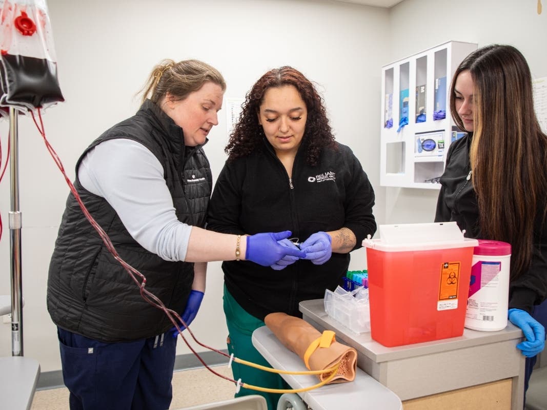 A professor at QCC is guiding students in the Medical Assistant Apprenticeship Degree Program.