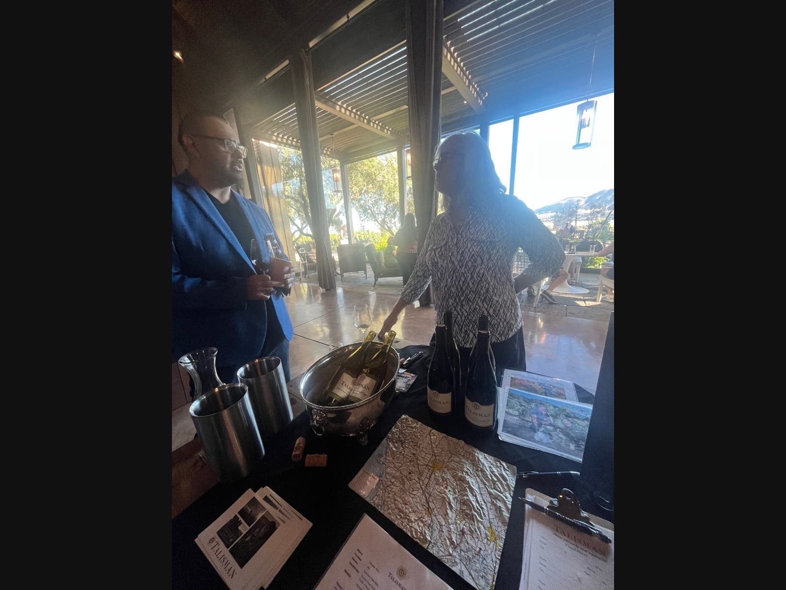 A winemaker talking to a visitor to the annual at Pour + Explore: Sonoma Valley held at Ram's Gate Winery, July 24, 2026. Glasses clinked, conversations flowed, and panoramic vineyard views framed an evening showcasing Sonoma Valley's newest releases. 