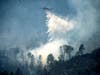 A helicopter drops water on the Pickett Fire burning in the Aetna Springs area of Napa County, Calif., on Sunday, Aug. 24, 2025. 
