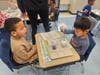 Students in Jodi Rebholz’s and Erica Castaldo’s kindergarten classes use droppers and colored water to test how much water a “cloud” can hold before it rains during a hands-on weather lesson.