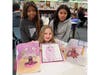 Second graders pose with their original monster designs alongside the clay and diorama versions created by eighth-grade art students.