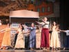 Ensemble members perform a choreographed dance number set in a Western-style backdrop during “Curtains.”