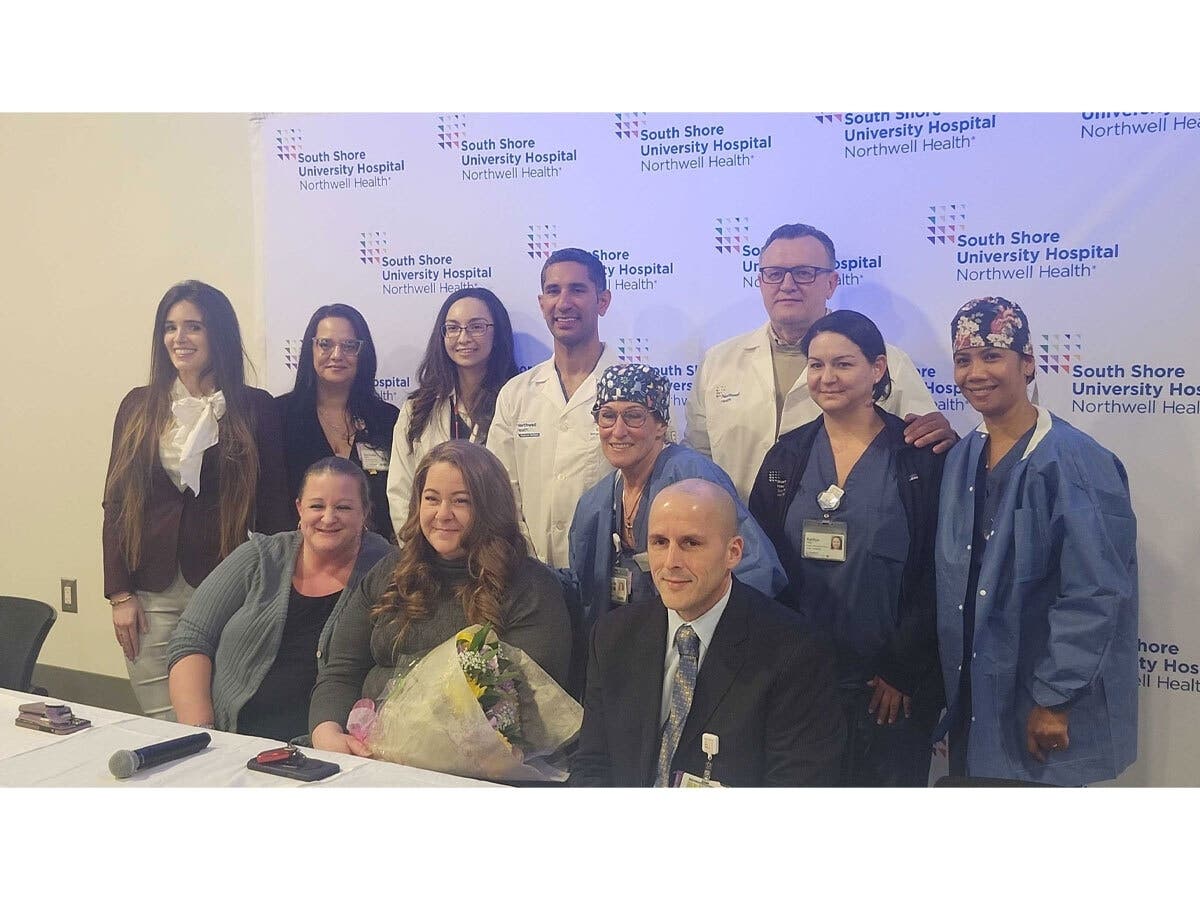 Keri Richards (seated, center with flowers) poses with the South Shore University Hospital doctors, nurses and staff who saved her life after a heart attack and cardiac arrest during the hospital’s “Thank a Lifesaver” event.
