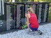 Eva Casale pauses at a memorial wall to honor fallen service members, placing flowers as part of Team E.V.A.’s mission to visit hundreds of Points of Honor along the route.
