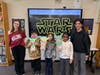 Students and helpers pose with their completed Yoda puppets during a hands-on Star Wars Day lesson at Mills Pond Elementary School.
