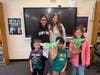 Students show off their handmade Yoda puppets alongside high school helpers during a Star Wars-themed activity at Mills Pond Elementary School